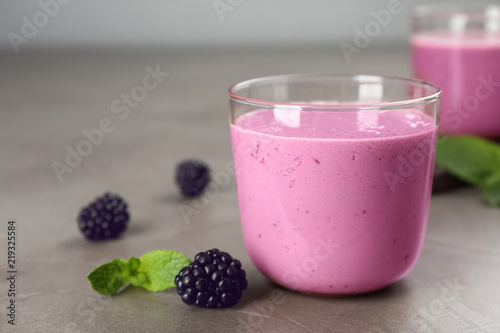 Glass with blackberry yogurt smoothie on grey table