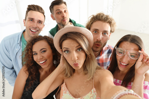 Group of happy young people taking selfie indoors