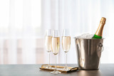 Glasses with champagne and bottle in bucket on table