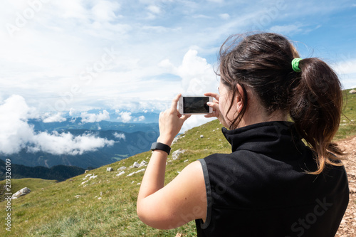 Young woman taking a picture with phone on mountain Sciliar