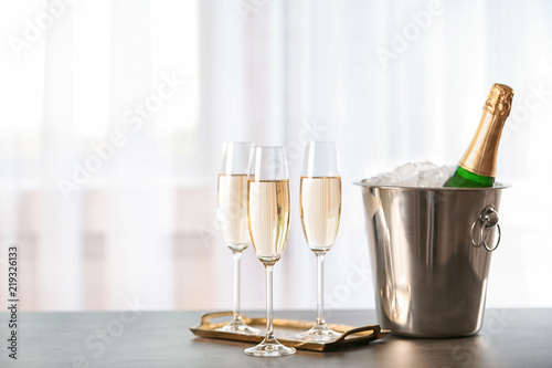 Glasses with champagne and bottle in bucket on table