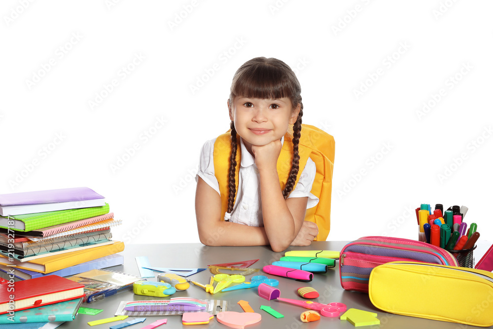 Cute girl sitting at table with school stationery against white background Cute girl sitting at table with school stationery against white background