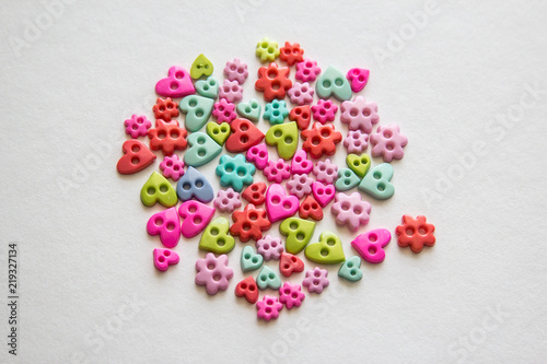 Mixed coloured bright buttons. Colored buttons in the shape of heart. Button plastic colorful on white background and copy space. Beautiful color buttons. Sewing buttons. Many color plastic.