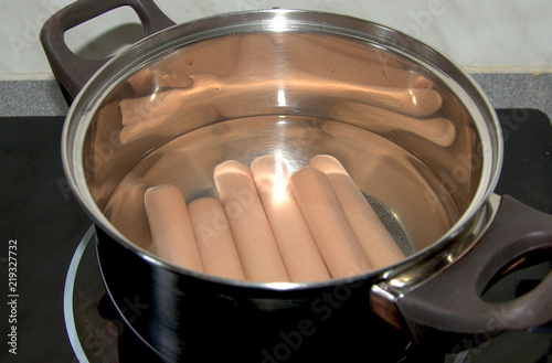 Pan with boiled sausages on the stove in the kitchen