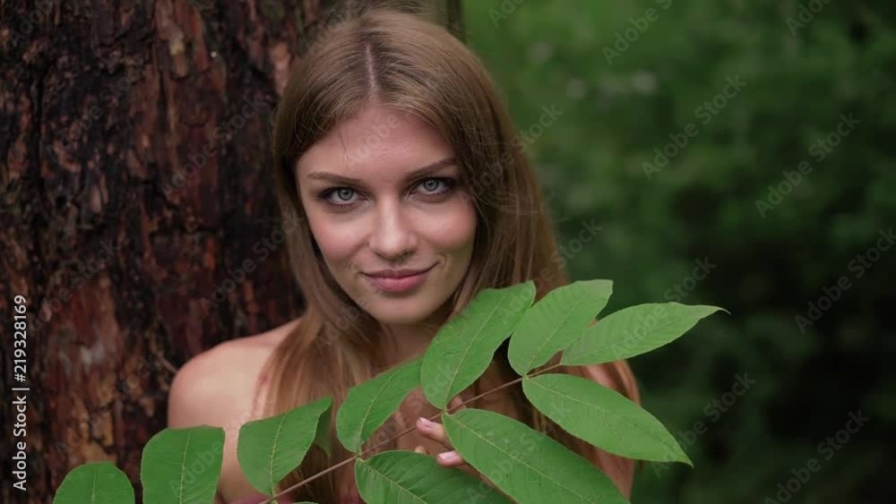 young woman without clothes holding a long leaves tree branch