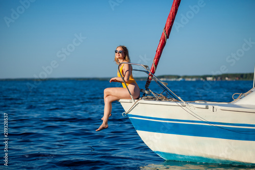 Girl in sunglasses sitting on the bow of the yacht