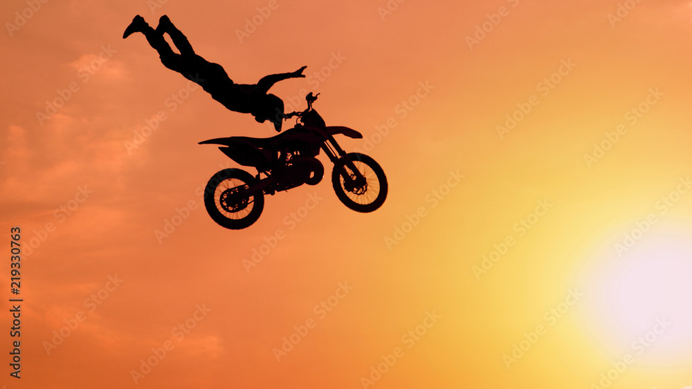 Extreme pro motocross biker jumping freestyle trick over the sun Extreme pro motocross biker jumping freestyle trick over the sun