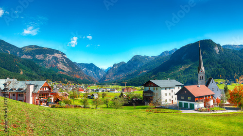 Alpine green fields and traditional wooden houses view of the Gosau village at autumn sunny day.
