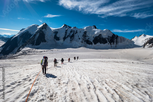 Canvas-taulu Group of Mountaineers with Backpacks is Roped Together and Ascending on Glacier