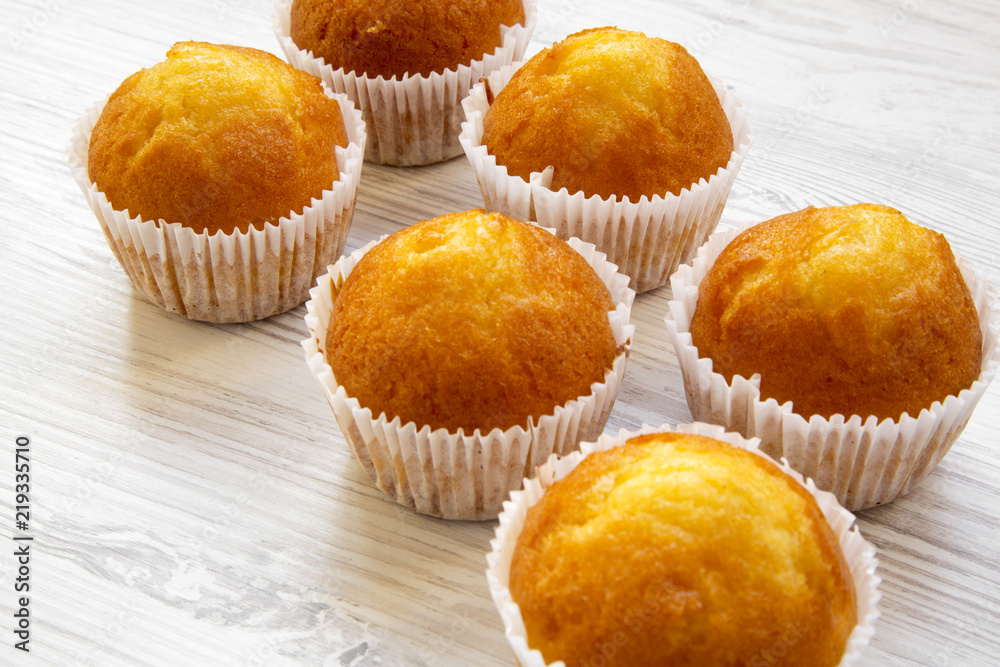 Fresh muffins on a white wooden table, side view. Close-up. Fresh muffins on a white wooden table, side view. Close-up.