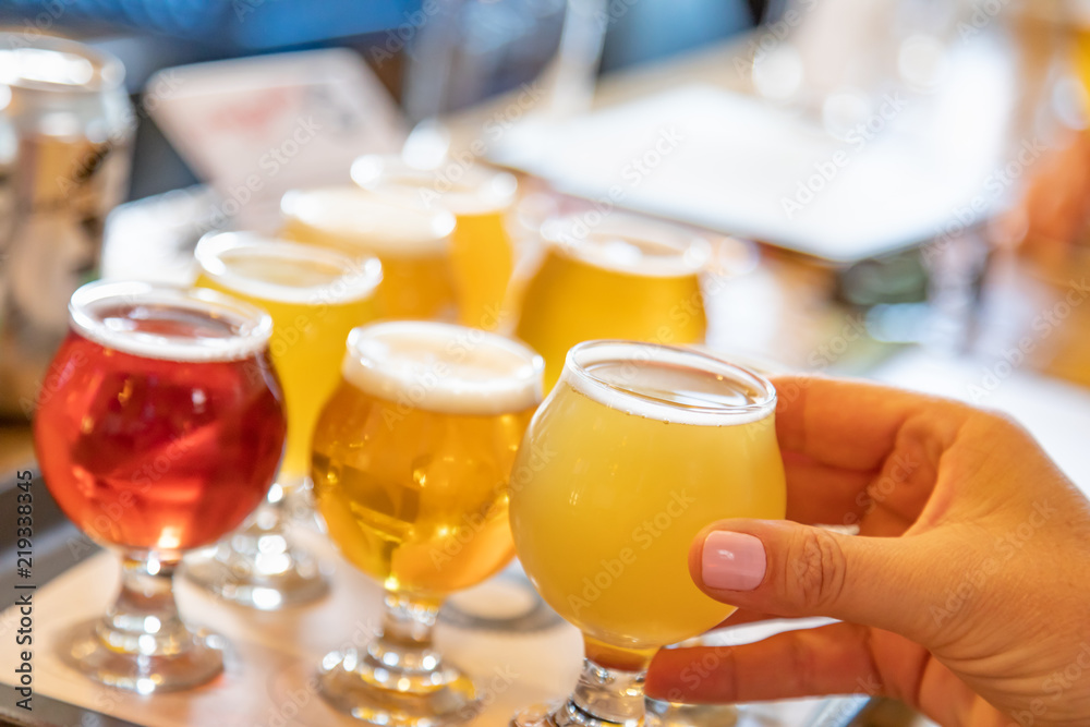 Female Hand Picking Up Glass of Micro Brew Beer From Variety on Tray Female Hand Picking Up Glass of Micro Brew Beer From Variety on Tray