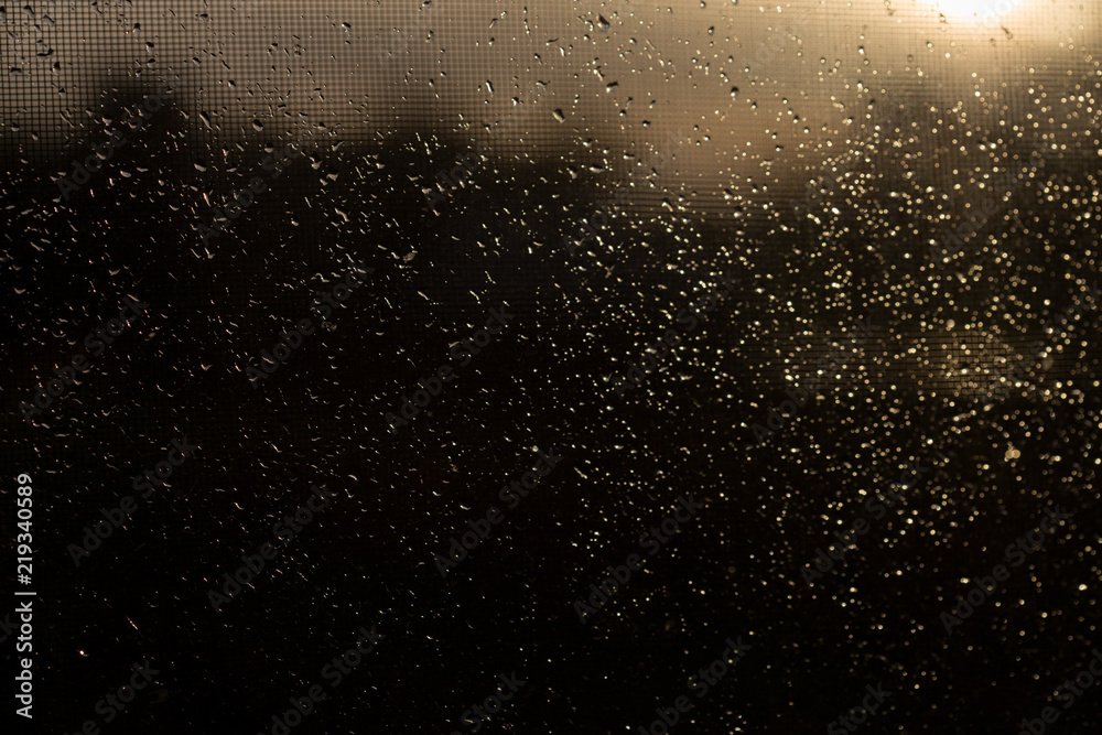 Rain outside the window during sunset. Bright texture of water droplets