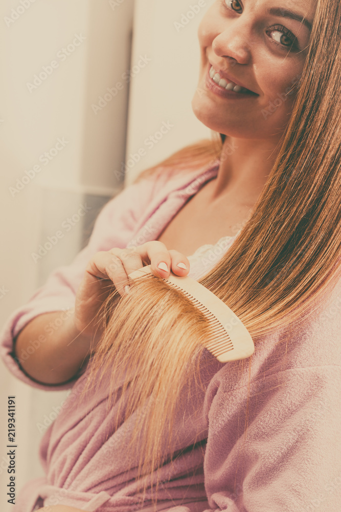 Fototapeta premium Woman combing her long hair in bathroom