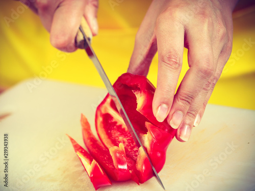 Woman preparing vegetables salad slicing red pepper