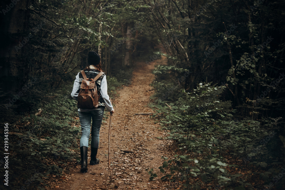 hipster traveler with backpack walking in woods. stylish woman hiking. wanderlust and travel concept with space for text. atmospheric moment