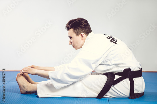 girl in karate suit kimono in studio at grey background. Female child shows judo or karate stans in white uniform with black belt. Individual martial art sport . body portrait