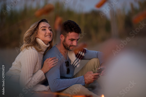 Group Of Young Friends Sitting By The Fire at beach