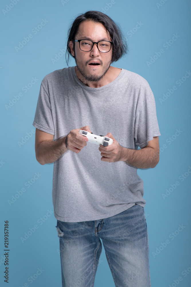 Young bearded man playing VR game in blue background. Young bearded man playing VR game in blue background.