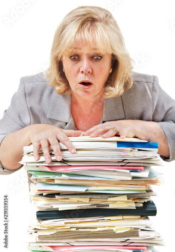 Mature woman trying to stop the pile of work from toppling