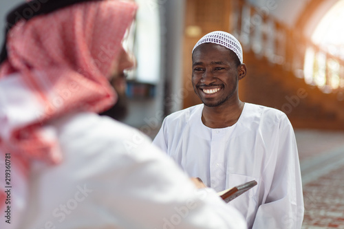 Two religious muslim man praying together inside the mosque photo