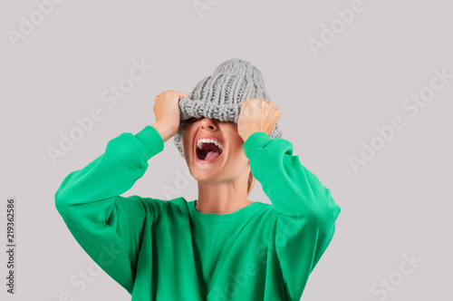 Crying emotional angry woman is pulling wool hat over her eyes photo