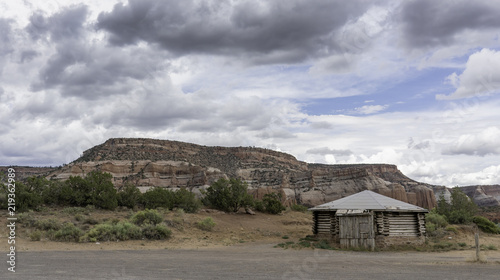 Navajo hogan under cloudy skies by red rocks