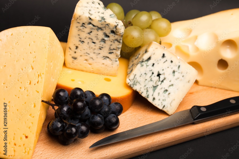 Knife, Cheese and Grape on the Wooden Platter on Black