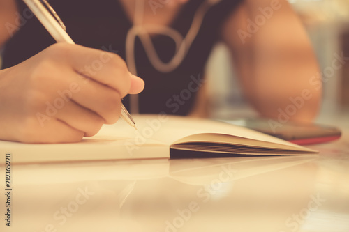 Copy space of woman hand writing down in white notebook with sun light background.