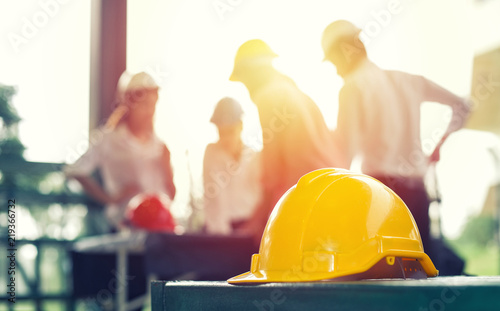 Yellow hard safety helmet hat for safety project of workman as engineer on together joining concept at construction site background.