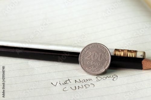 Two hundred Vietnam Dong coin on reverse (VND) with black and white pencil on the book.