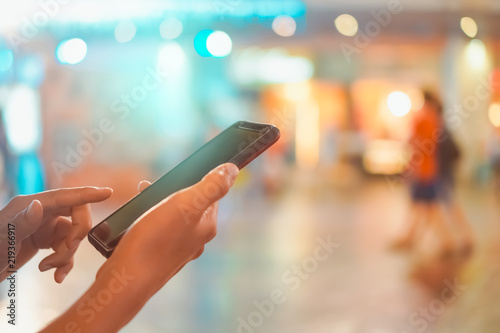 Woman hand using smartphone in mall