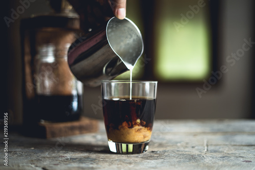 Black coffee in glass And milk is pouring