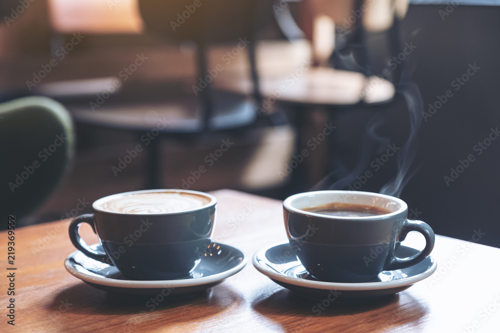 Fototapeta Closeup image of two blue cups of hot latte coffee and Americano coffee on vintage wooden table in cafe