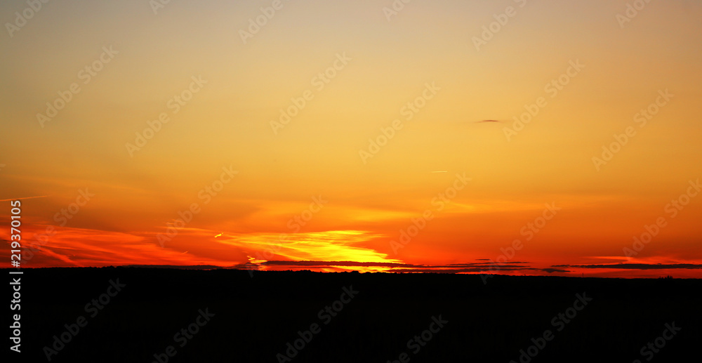 Beautiful photo of a bright sunset with clouds over a field