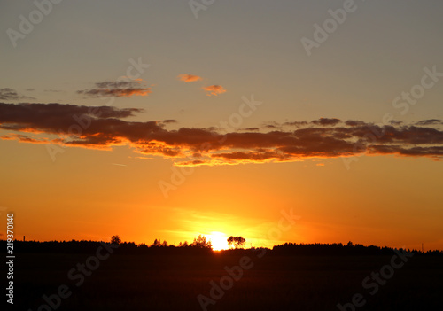 Beautiful photo of a bright sunset with clouds over a field