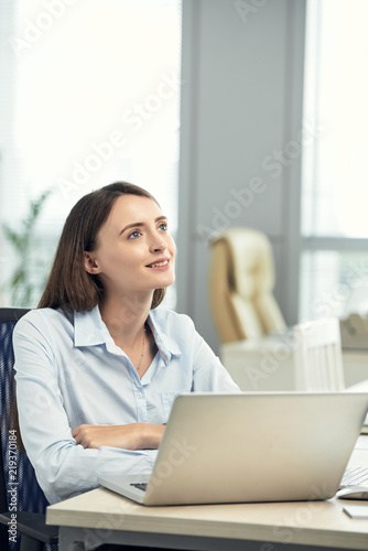 Portrait of young smiling business lady at her office table