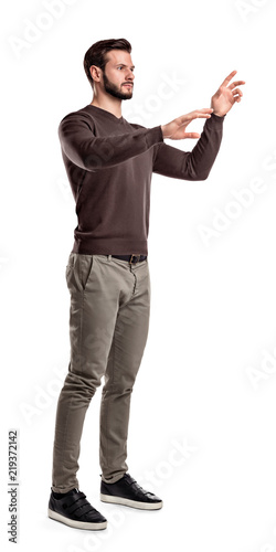 Foto A young man in fashionable casual closes stands on a white background with hands as if pressing invisible buttons