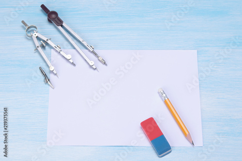 against the background of the blue table is a white sheet and a compass for drawing eraser. photo