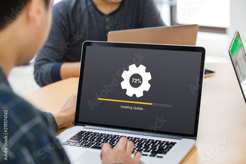 Man working and Installing update process with gearbox percentage progress and loading bar on laptop / computer screen at office