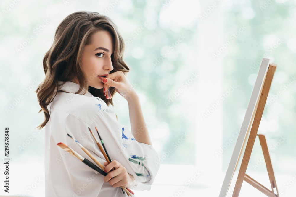 Beautiful woman artist with brushes posing in her studio Beautiful woman artist with brushes posing in her studio