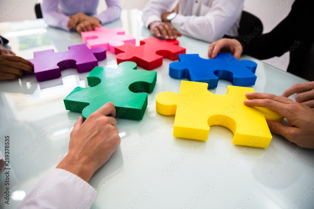 Group Of Businesspeople Solving Jigsaw Puzzle Group Of Businesspeople Solving Jigsaw Puzzle