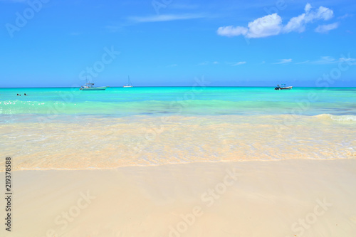 coast of the Caribbean Sea, white sand, beautiful azure water of the sea, boats and boats on the horizon, blue sky covered with light white clouds © Nemo67