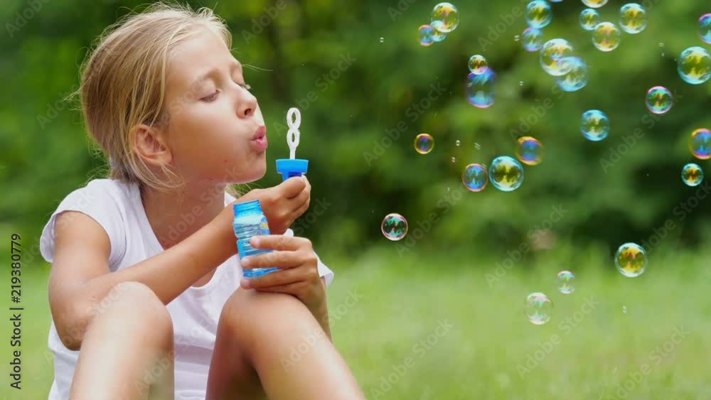 Nine-year-old girl playing with soap bubbles outdoor. Slow motion. Nine-year-old girl playing with soap bubbles outdoor. Slow motion.