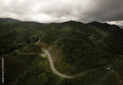 Aerial view of countryside road passing through the lush greenery and foliage tropical rain forest mountain landscape in the Northern Thailand
