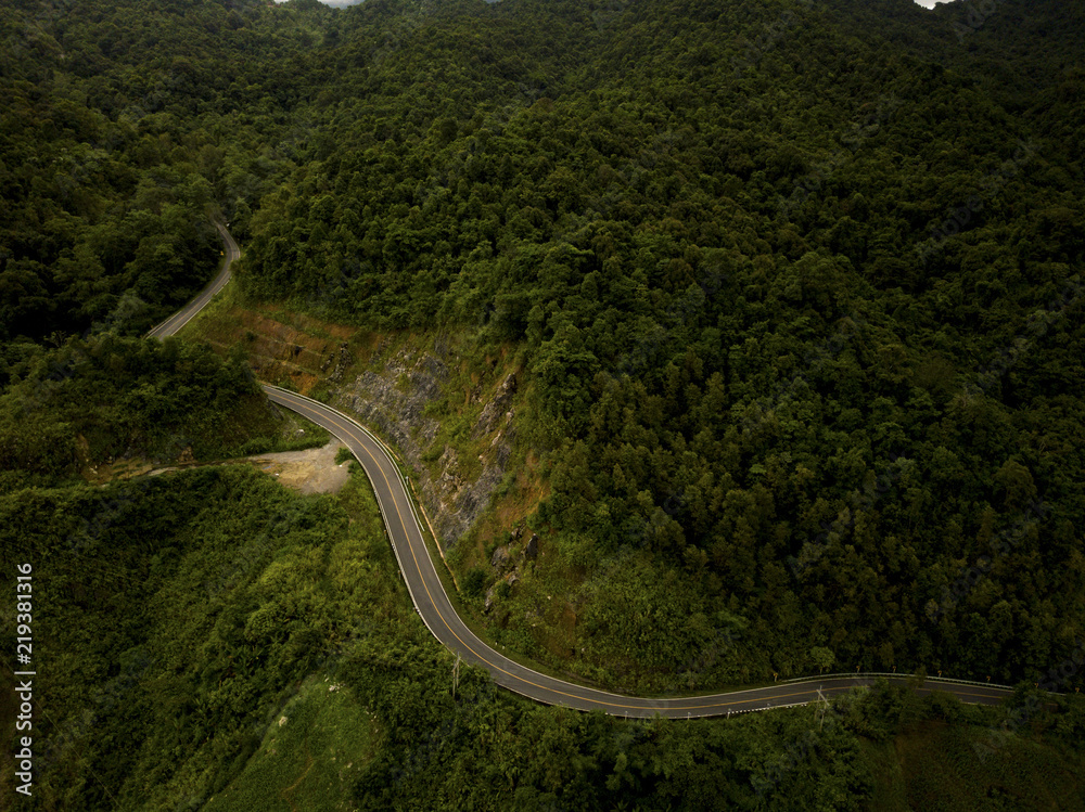 Aerial view of countryside road passing through the lush greenery and foliage tropical rain forest mountain landscape in the Northern Thailand Aerial view of countryside road passing through the lush greenery and foliage tropical rain forest mountain landscape in the Northern Thailand