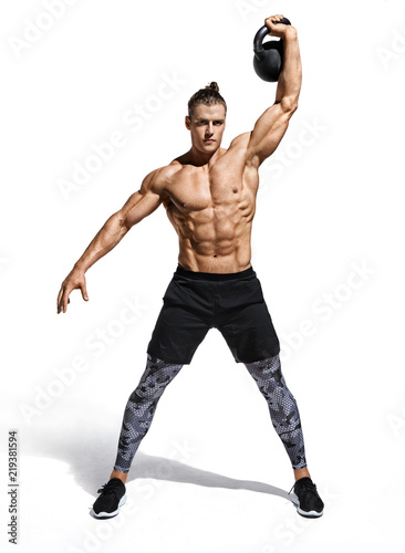 Young muscular guy training with kettlebell. Photo of handsome man with naked torso on white background. Strength and motivation. Full length