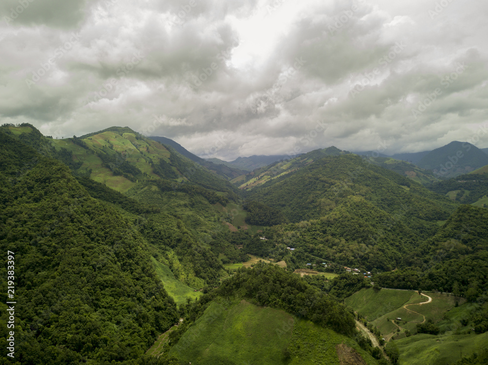 Aerial view of a village in the lush green rain cloud cover tropical rain forest mountain during the rainy season on the Doi Phuka Mountain reserved national park the northern Thailand