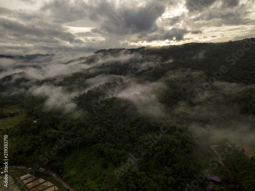 Aerial view of a village in the lush green rain cloud cover tropical rain forest mountain during the rainy season on the Doi Phuka Mountain reserved national park the northern Thailand