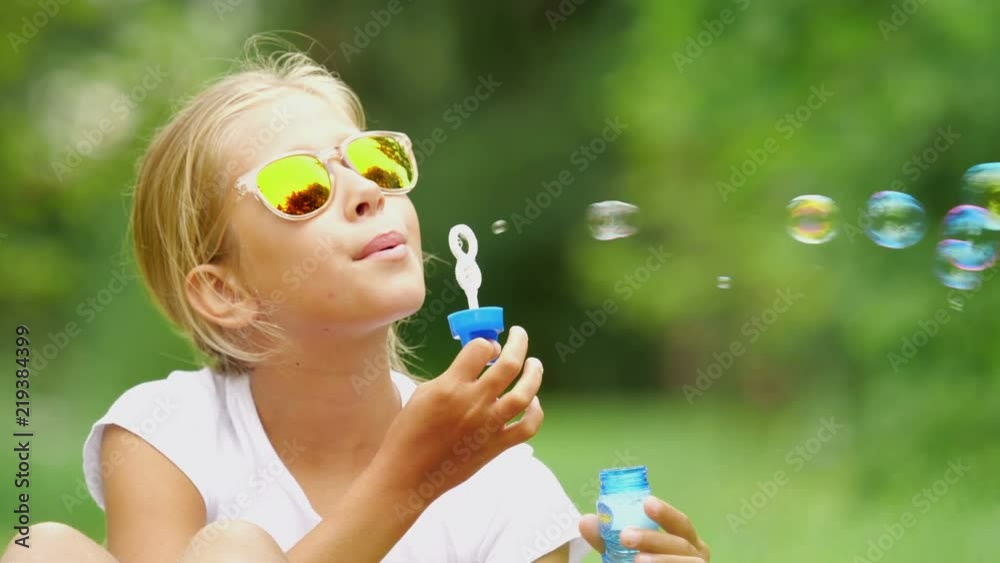 Nine-year-old girl plays with soap bubbles in the summer garden. Nine-year-old girl plays with soap bubbles in the summer garden.