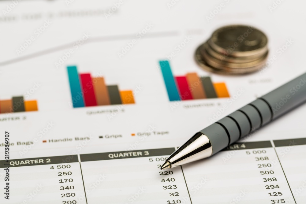 Pen and Coins on Business Graphs and Charts Pen and Coins on Business Graphs and Charts